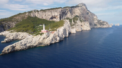 Lighthouse and Beach of Capri in summer season. View from a moving drone.