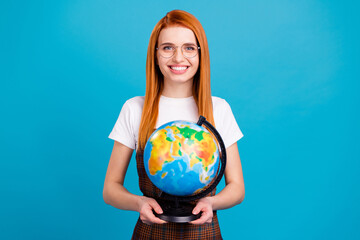 Photo of young school girl happy positive smile hold globe geography study isolated over blue color...
