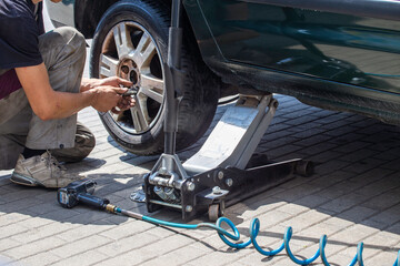 Replacing the wheel in the car. Car mechanic. Jack, bolts, car service. Vulcanization - obrazy, fototapety, plakaty