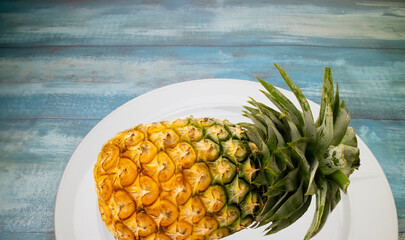 a fresh pineapple on white plate on wooden table,food,juicy fruit,