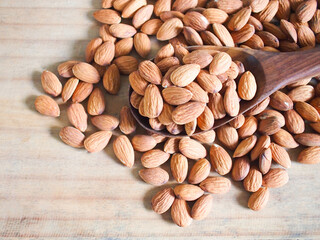 Seed almonds on wooden spoon on wood background. 