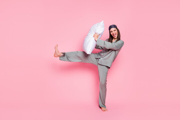 Photo of sweet charming young woman nightwear smiling pillow fighting isolated pastel pink color...