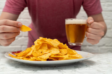 person holding a beer and chips