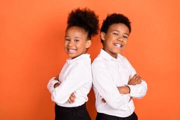 Profile side photo of two young black kids happy positive smile pupil uniform crossed hands isolated over orange color background