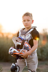 Child rider on motorcycle. Small biker dressed in a protective suit and helmet. The kid is engaged in motocross