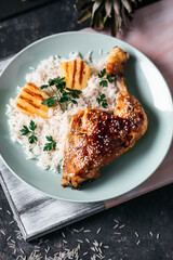 Roasted Chicken thighs with rice, pineapple on a wooden board