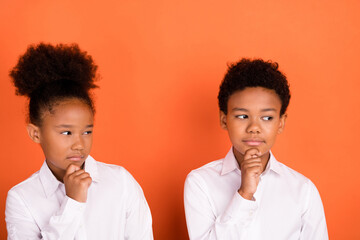Photo of two young little afro kids thoughtful hand touch chin look empty space isolated over...