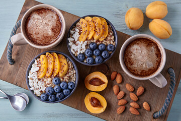 Oatmeal with blueberries and apricots, fruits, nuts and coffee