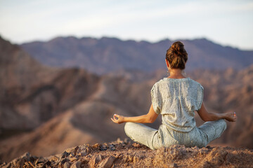 Woman practicing yoga in the mountains in the desert - 448089885