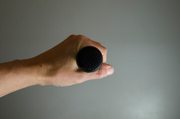 black microphone in hand, from front isolated on gray background