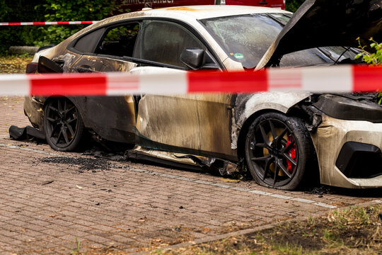 Property loss crime scene: daylight closeup view of exterior of parking lot where arsonist set fire to parked vehicles. Vandalism on the street leaves several cars burned, in irreparable state