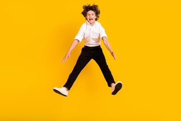 Fototapeta na wymiar Full length photo of funny small brunet boy jump wear uniform isolated on yellow color background