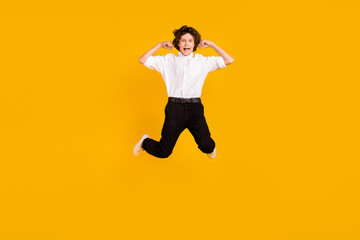 Fototapeta na wymiar Full length photo of impressed small brunet boy jump wear uniform shoes isolated on yellow color background