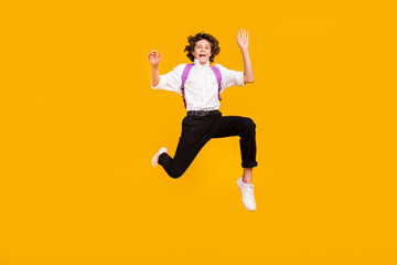 Fototapeta na wymiar Full length photo of impressed small brunet boy jump wear uniform shoes isolated on yellow color background