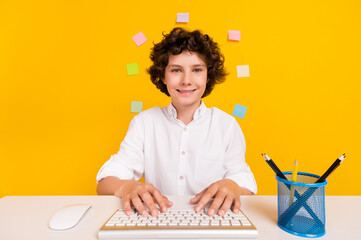 Photo of sweet pretty school boy wear white shirt smiling typing modern gadget isolated yellow color background