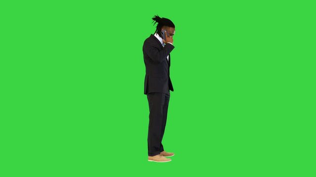 Black man in office suit talking on mobile phone on a Green Screen, Chroma Key.