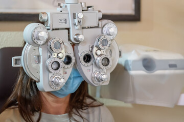Young girl in mask at the ophthalmologist's appointment. Eyesight check. Ophthalmic device. Close-up.