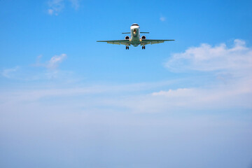 Fototapeta na wymiar Passenger commercial airplane landing against blue cloudy sky.
