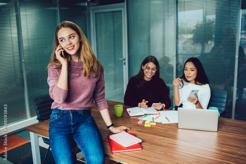 Poster happy caucaisan employee using cellular device for friendly calling during cooperation with blurred 