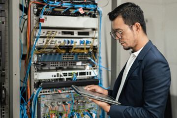 Stock photo of a young network technician holding tablet working to connecting network cables in...