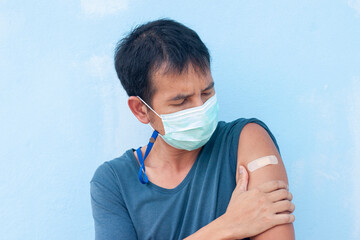 Asian man wearing a mask looks down on his vaccinated arm to prevent coronavirus (Covid-19).