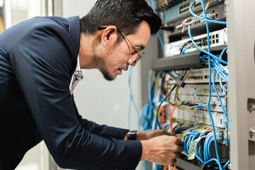 Stock photo of a young network technician holding tablet working to connecting network cables in...