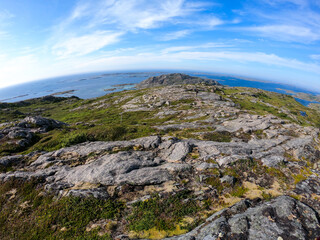 Fototapeta na wymiar View from above of a rock cliff and the ocean bending in a circle on the horizon under blue sky in the evening. Valoy. Norway. Islands in blue sea.