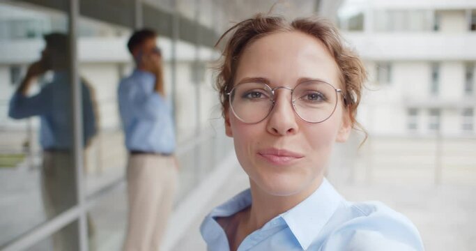 Young businesswoman with brace having video call standing outside office building