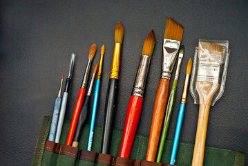 Paint brushes in a black cover. Tools for artists of different shapes and sizes.