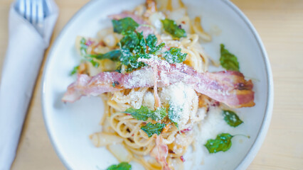 Pasta Carbonara. Spaghetti with bacon, parsel and parmesan cheese. Pasta Carbonara on white plate with parmesan on dark background. Italian food concept.