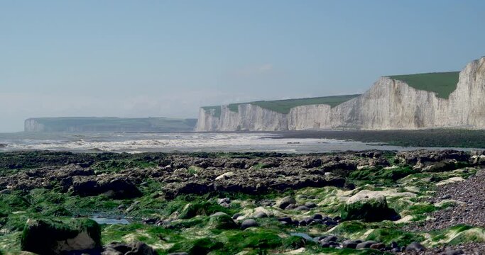 A hot summers day at Eastbourne's Burling Gap. The tide is going out leaving glistening water on the rocks and drenched green seaweed. Fresh, clean coastal scenery at this popular tourist beach.