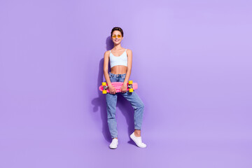 Full length body size photo girl in jeans keeping skateboard wearing sunglass isolated pastel violet color background