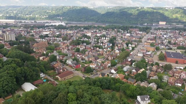 A slow forward aerial view of Ambridge, a small working class river town in Western Pennsylvania. Ohio River in the distance. Pittsburgh suburbs.  	