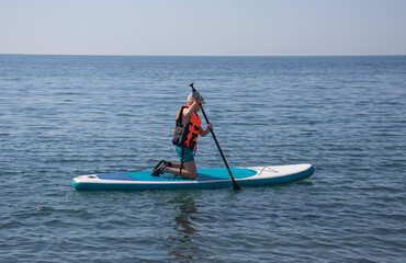 Naklejka premium boy sailing on Sup board on the sea