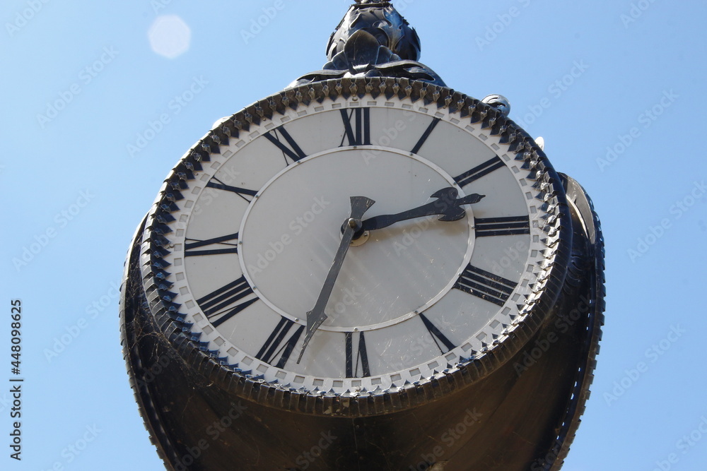 Wall mural metal dial and chairs of a street clock in the park