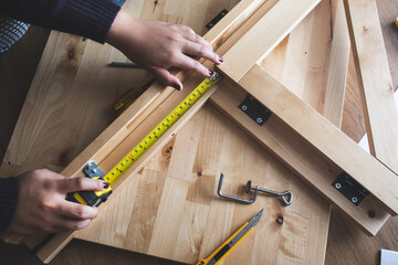 Woman assembly wooden furniture,fixing or repairing house with tape measures