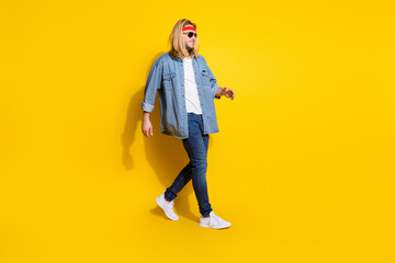 Photo of cool funky young guy dressed denim shirt smiling walking empty space isolated yellow color background