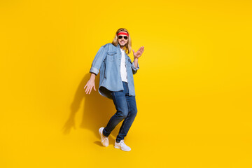 Fototapeta na wymiar Photo of sweet funny young gentleman wear jeans shirt dark glasses dancing smiling isolated yellow color background