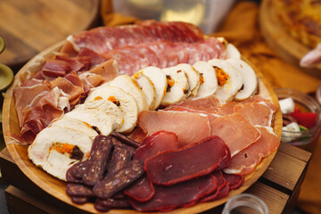 assorted meat cuts. sausage, meatloaf, ham on a round wooden plate. 