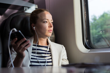Businesswoman communicating on mobile phone while traveling by train.
