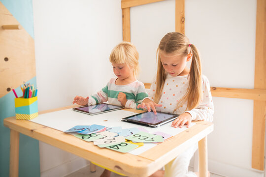 Children at home school study in a tablet, preschool girls study computer science in kindergarten