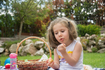 Little girl having a picnic in their garden on a hot summer day