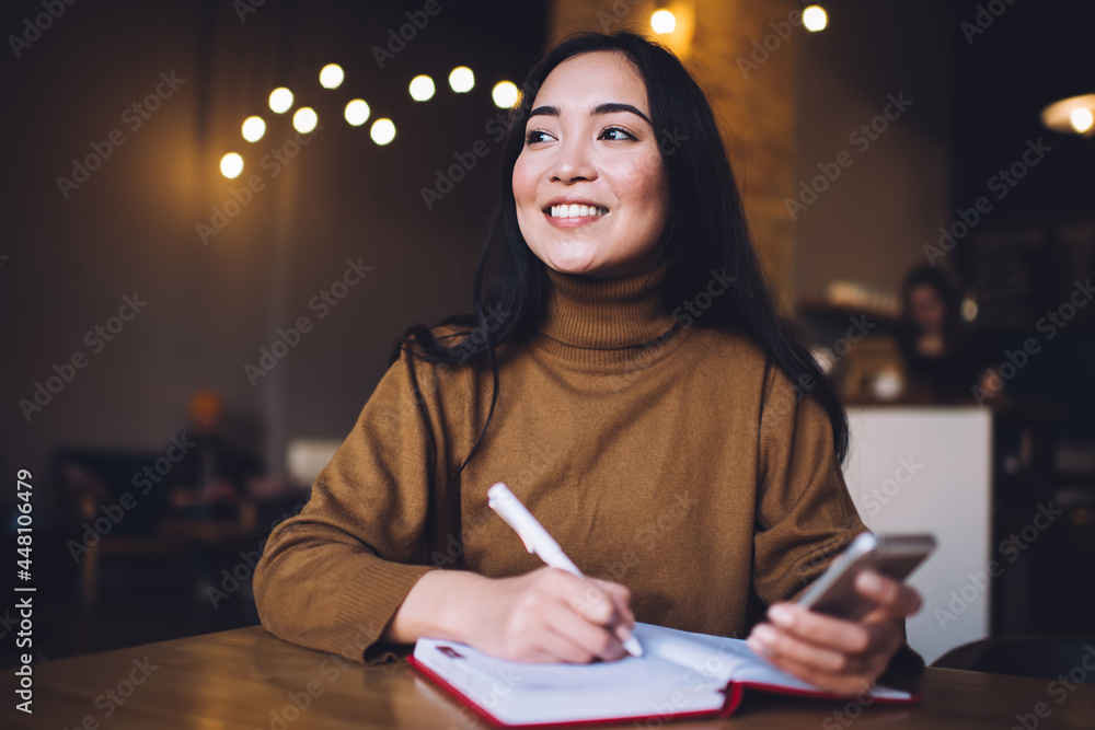 Poster cheerful hipster blogger with cute smile on face enjoying time for smartphone networking and creatin