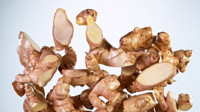 Super slow motion of cut ginger roots flying in the air on gradient background. Filmed on high speed cinema camera, 1000 fps.