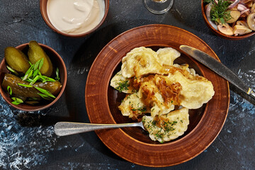 Vareniki with potato filling and fried onions served with sour cream, pickles