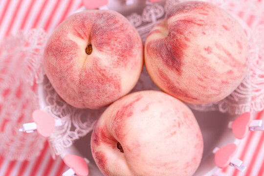 Three ripe pink peaches in a bowl. Delicate velvety and juicy peaches fruits