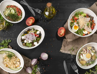 Five different salads on black wooden table