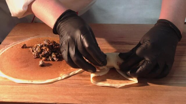 the chef wraps fried minced meat with mushrooms in pancakes