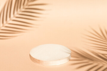 Round wooden podium for food products or cosmetics on a bright brown background with palm tree...