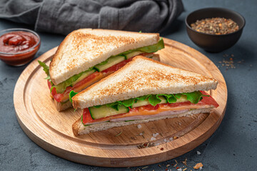 Fried sandwiches with vegetables, ham and cheese on a board on a dark blue background. Side view, close-up.
